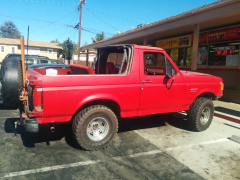 1988 Ford Bronco - Red 1988 Ford Bronco parked outside a store, with its top removed.