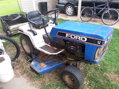 2002 Ford Expedition - This Ford YT 16 lawn tractor is parked outdoors next to a bicycle and a car.