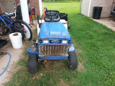 2002 Ford Expedition - A blue Ford riding mower sits in a grassy yard next to a white bucket and a bicycle.