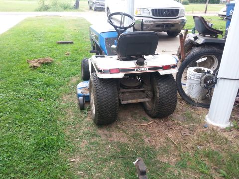 2002 Ford Expedition - A white and blue Ford lawn tractor is parked on grass next to a white Ford pickup truck.