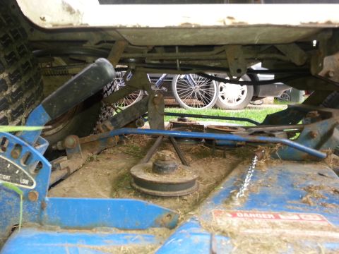 2002 Ford Expedition - The underside of a lawn mower reveals its mechanical components, with other vehicles partially visible in the background.
