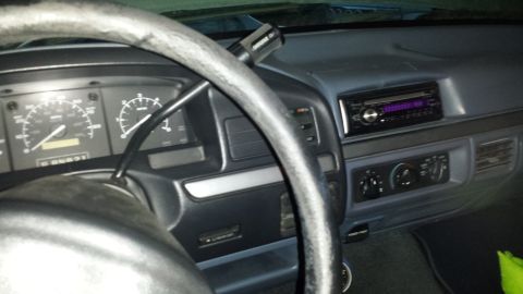 1996 Ford Bronco - The interior of a vehicle shows the dashboard, steering wheel, and radio.