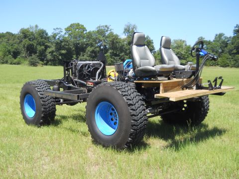 1992 Ford Bronco - This custom-built vehicle features a bare chassis, two bucket seats, and oversized tires with blue rims.