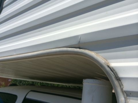 1986 Yugo GV - A crack is visible in the white corrugated siding of an RV, near a rounded edge.