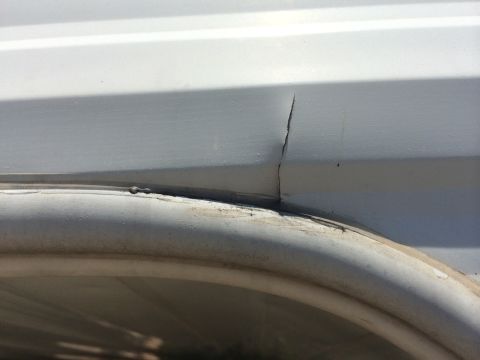 1986 Yugo GV - A close-up view shows a crack in a white panel, with a curved trim piece below.