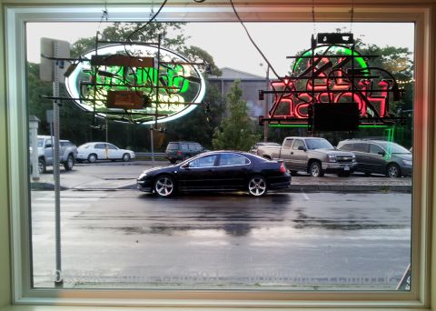 2002 Chrysler 300M - A black 2002 Chrysler 300M is seen from the side, parked on a wet asphalt surface with neon signs in the background.