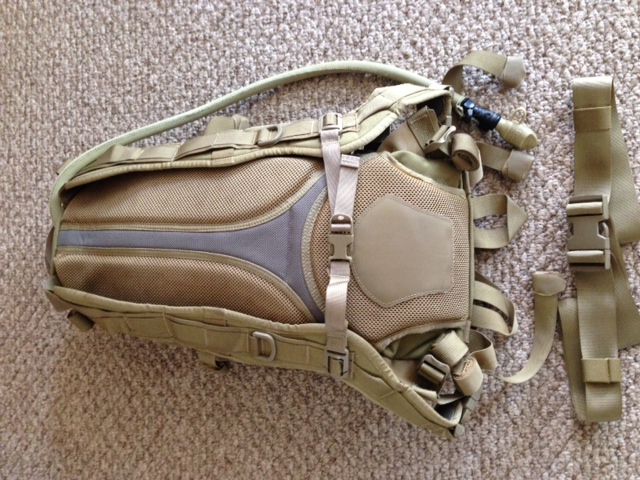 Tan tactical hydration backpack with straps and a water tube. Text at bottom reads "SUPER MOTORS www.supermotors.net"