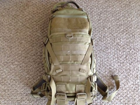 2005 Audi S4 - A tan tactical backpack is shown from the front, resting on a carpeted surface. The image includes a watermark for SuperMotors.net.