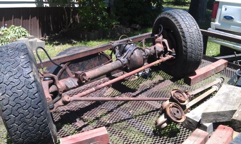 1990 Ford Bronco - Front axle assembly with tire, likely for a truck or SUV, resting on a trailer.