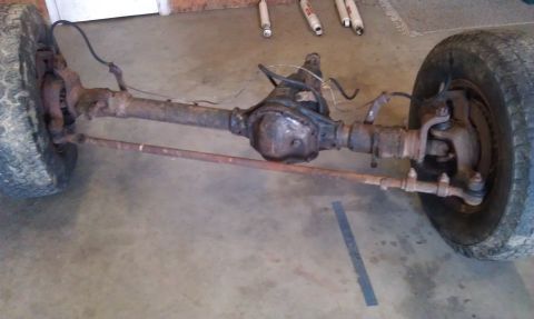 1990 Ford Bronco - This is a front axle assembly, likely from a truck or SUV, with visible tires and brake components.