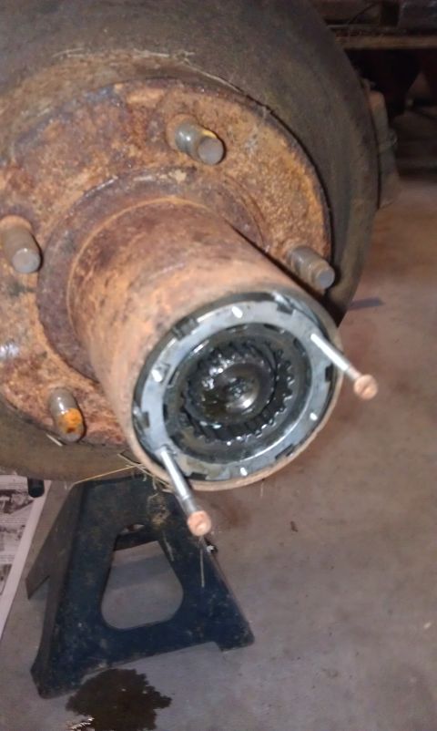 1990 Ford Bronco - Close-up view of a heavily rusted wheel hub assembly, showing the internal locking mechanism, resting on a black jack stand.