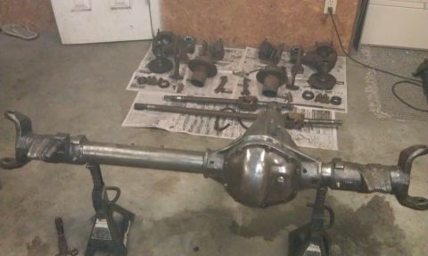 1990 Ford Bronco - Various automotive differential and axle components are displayed on the floor, some resting on jack stands.