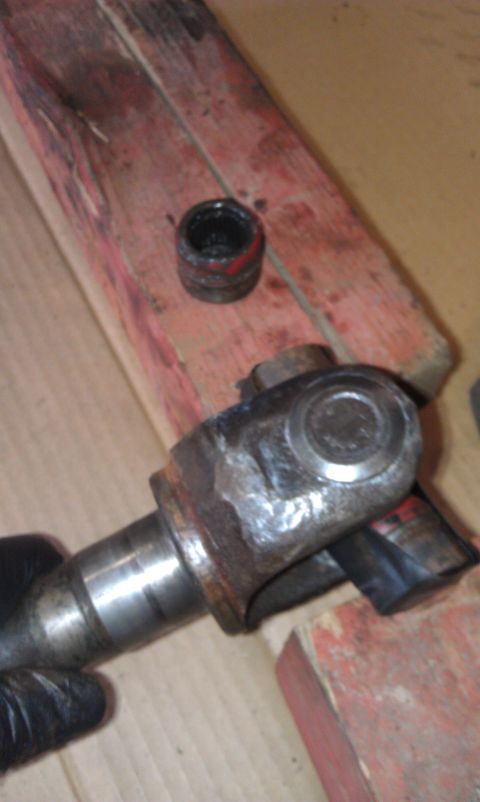 1990 Ford Bronco - Close-up of a driveshaft universal joint, showing wear and red and black markings, placed on wooden blocks.