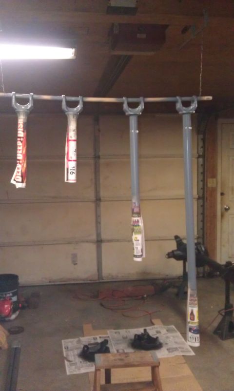1990 Ford Bronco - Suspension parts are hanging and appear to be prepped for painting in a garage setting.