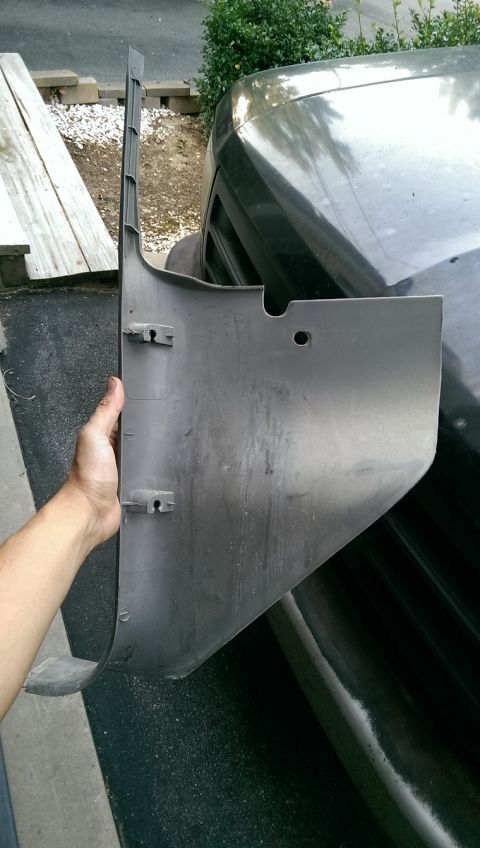 1996 Ford F-150 - A person holds a detached plastic trim piece against the side of a dark-colored vehicle.