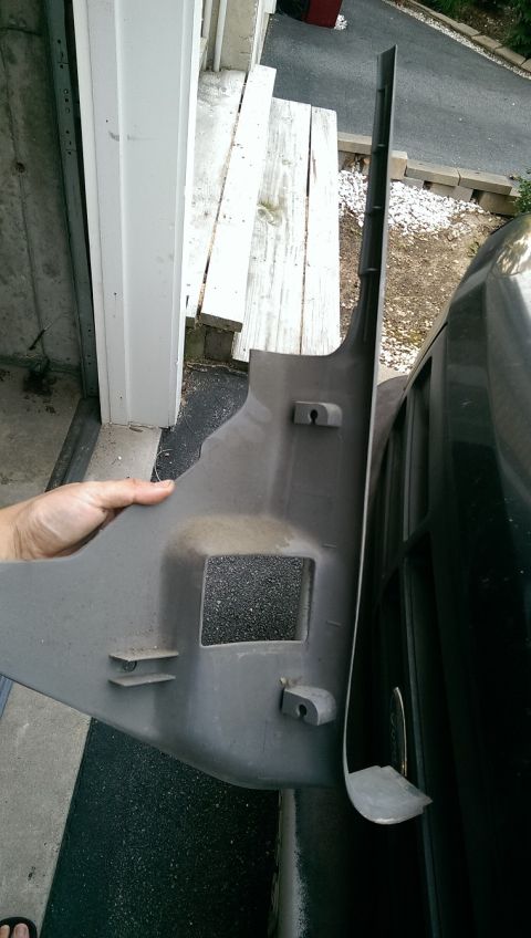 1996 Ford F-150 - A gray plastic interior trim panel is held up next to a dark vehicle.