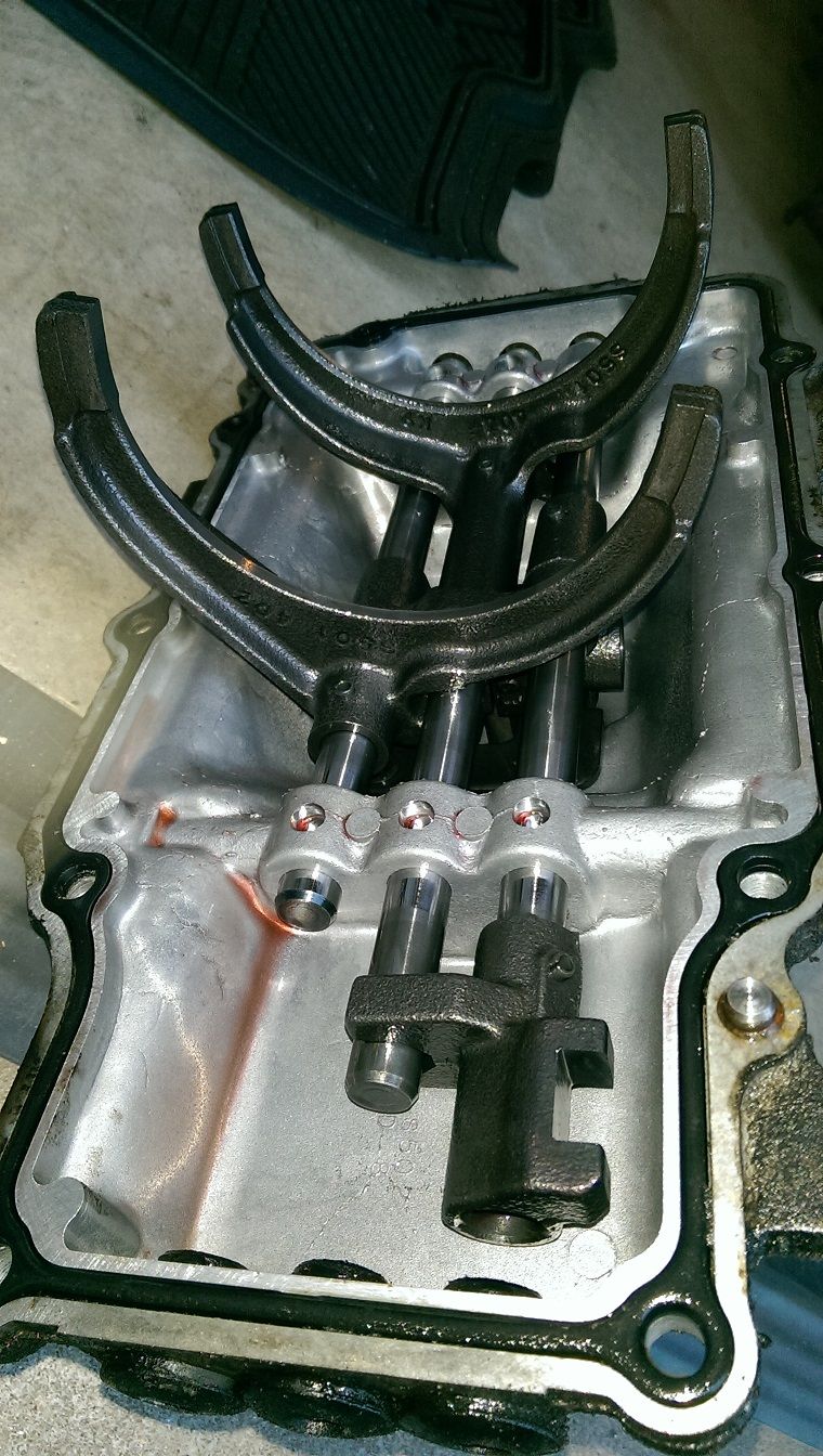 Transmission shift forks inside a metal casing with some red fluid visible