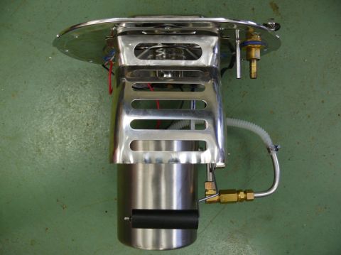 Chrome fuel pump assembly with black roller and brass fittings against a green background