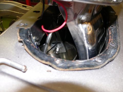 Fuel tank opening with a red wire and metal components visible