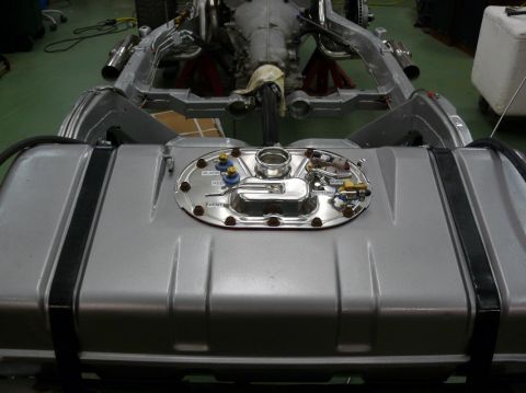 Silver fuel tank with chrome sending unit and fittings, part of a vehicle chassis visible above