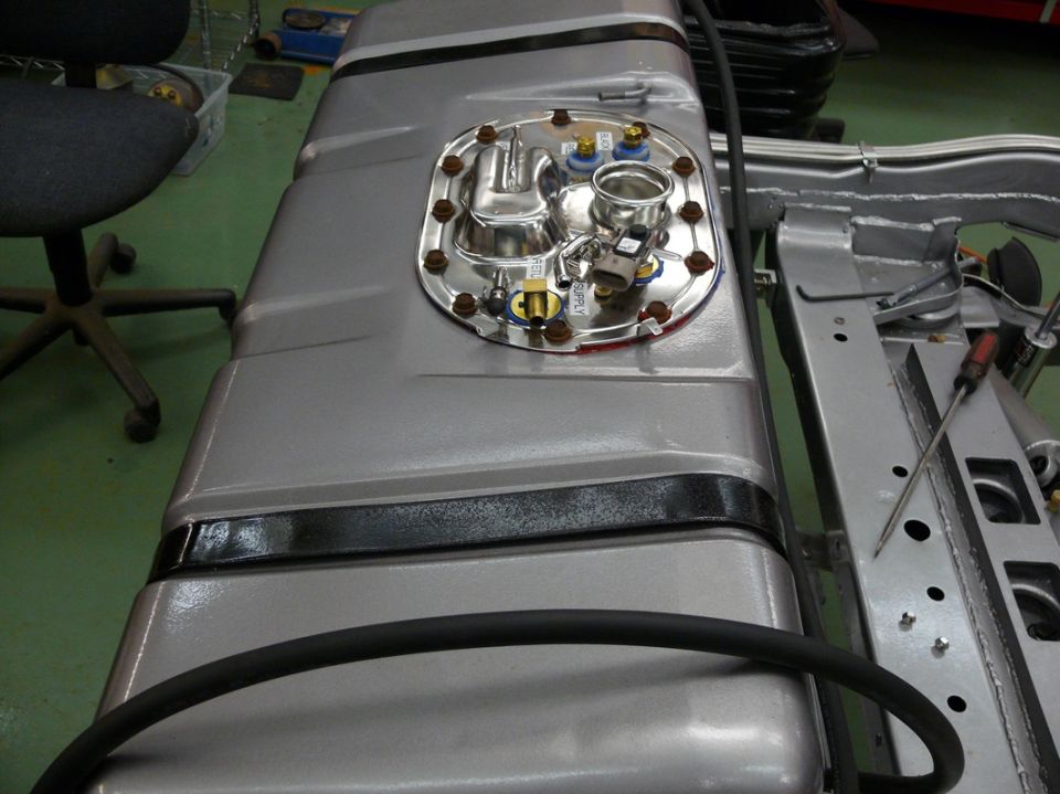 Silver fuel tank with chrome sending unit and black banding, mounted to a chassis
