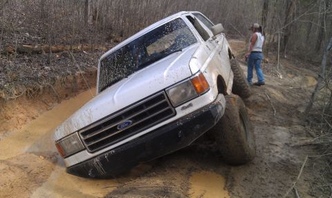 1990 Ford Bronco - White 1990 Ford Bronco tackling a challenging muddy off-road course.