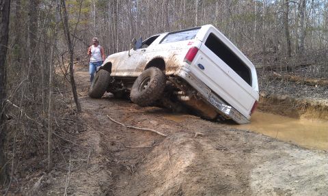 1990 Ford Bronco - A white 1990 Ford Bronco navigates a challenging muddy off-road course.