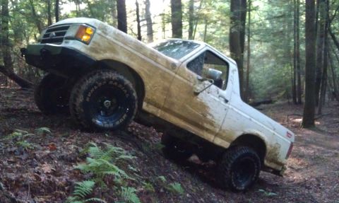1990 Ford Bronco - This 1990 Ford Bronco navigates a steep, muddy incline in a wooded area.