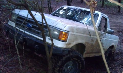 1990 Ford Bronco - This 1990 Ford Bronco navigates a wooded trail, its tires covered in mud.