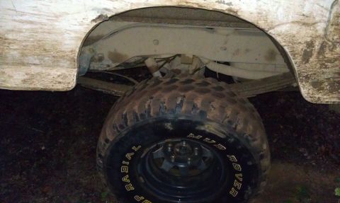 1990 Ford Bronco - Close-up view of a muddy rear wheel well and tire, showing the 'Mud Rover' radial tire branding.