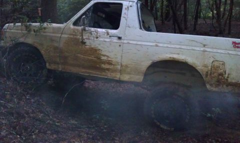 1990 Ford Bronco - White 1990 Ford Bronco navigating a muddy trail.