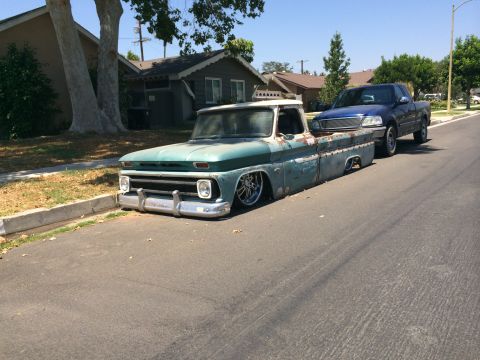 1968 Ford Mustang - A heavily modified vintage pickup truck sits low on its suspension next to a modern pickup.