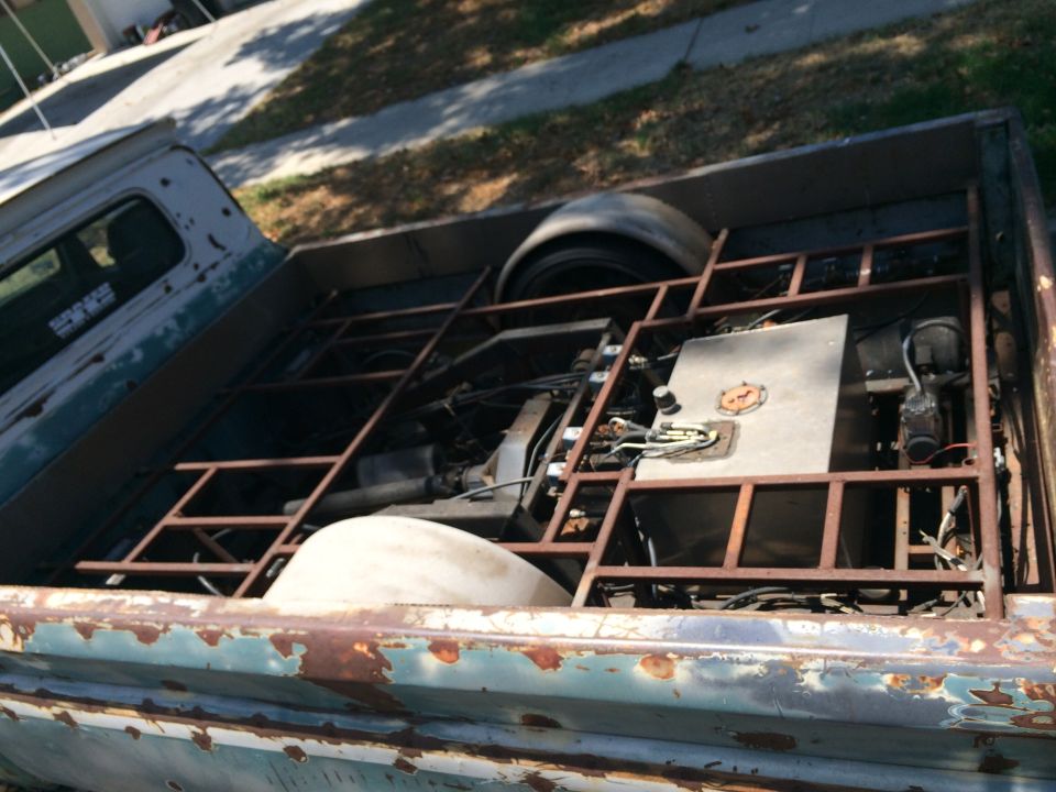 Pickup truck bed showing custom metal framing, fuel tank, and rear axle assembly