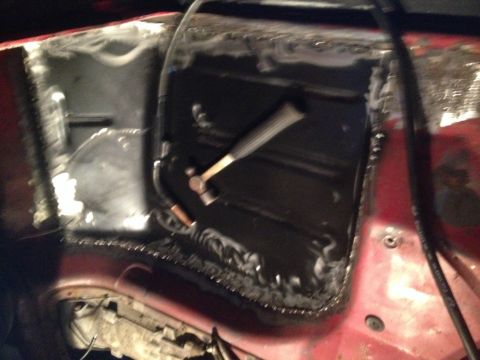 1978 Ford Bronco - Close-up of a vehicle's floor pan undergoing repair, with a hammer resting on the metal.