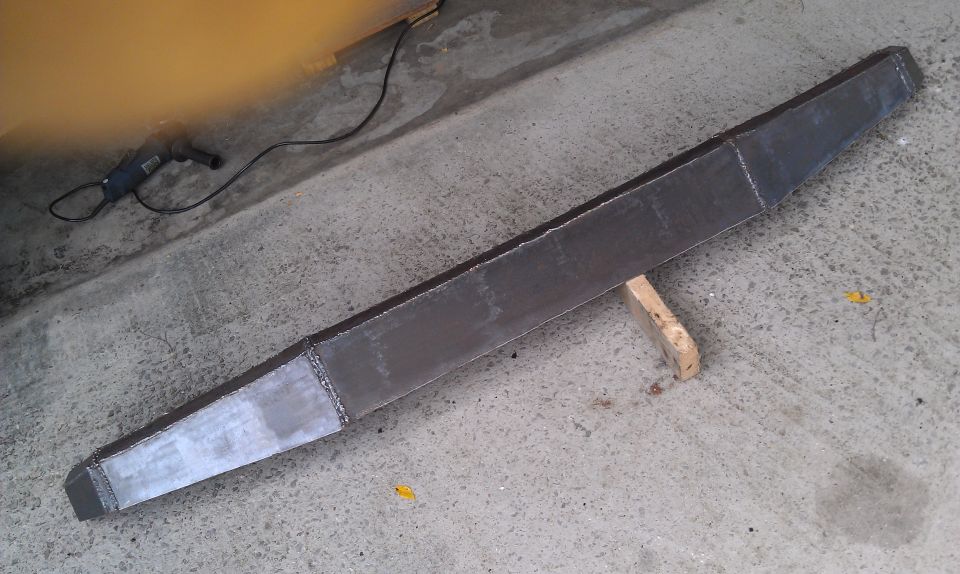 Fabricated steel bumper on concrete floor with grinder nearby