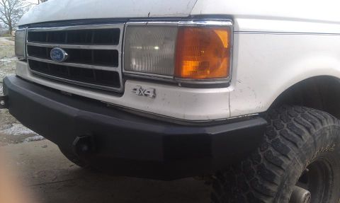 1990 Ford Bronco - Close-up of a white Ford truck's front end, a prominent grille and 4x4 badging.