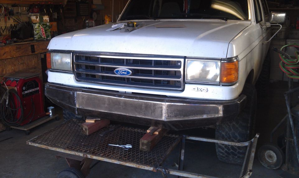 1990 Ford Bronco front end with custom steel bumper, sitting on a lift