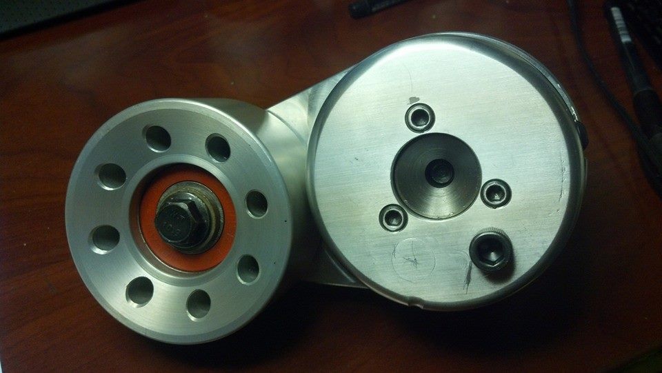 Two machined aluminum pulley/hub parts side by side on a wood desk