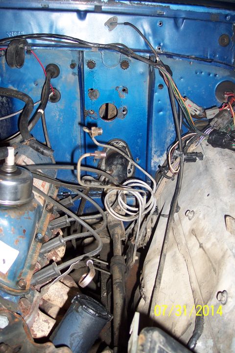 1978 Ford Bronco - Close-up view of the engine bay, showing complex wiring and brake lines against a blue firewall.