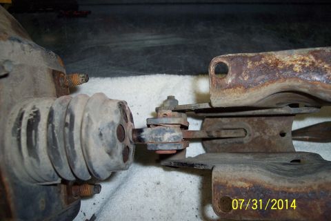 1978 Ford Bronco - Close-up view of a corroded brake caliper and linkage mechanism, showing a rubber boot and mounting bolts.
