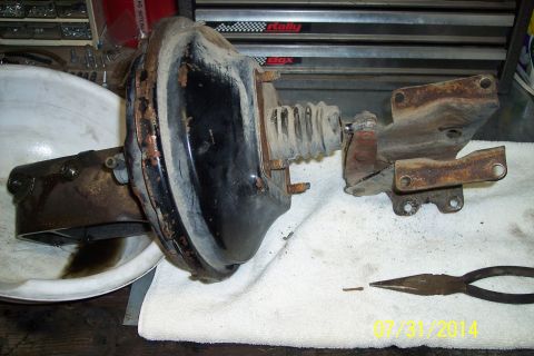 1978 Ford Bronco - Brake booster and master cylinder assembly shown with tools and a pin on a workbench.