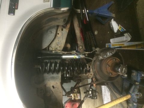 1996 Ford Bronco - Close-up of the front suspension of a 1996 Ford Bronco, showing the coil spring and shock absorber assembly.