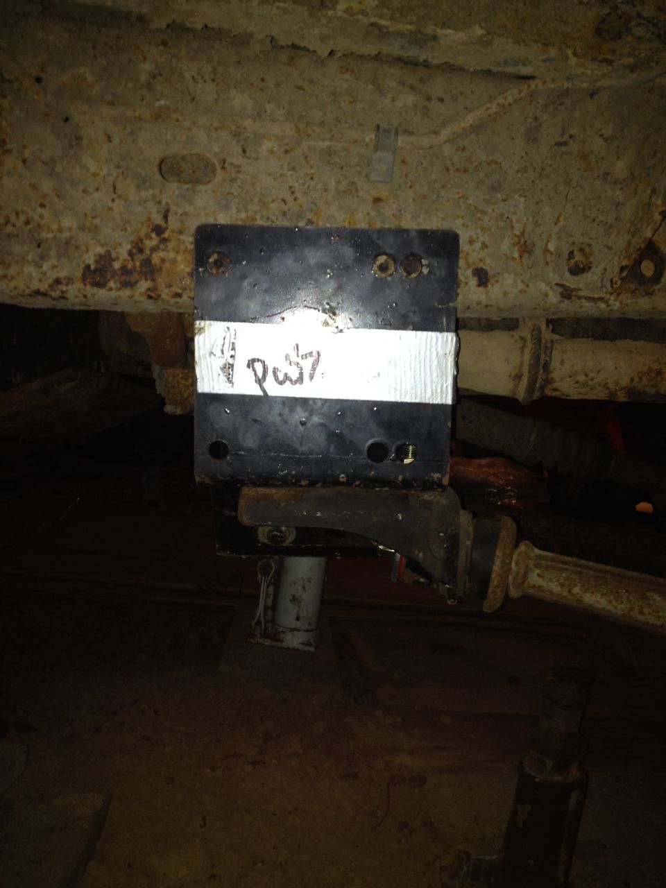 Underbody part with handwritten label 'Pw7' on white tape