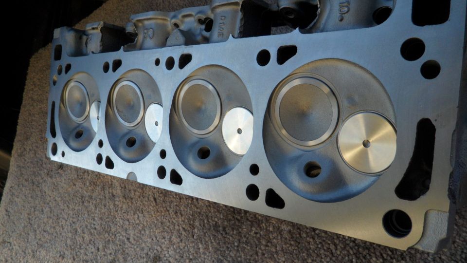Engine cylinder head with four combustion chambers visible. Text '50' and '01AE' stamped on top