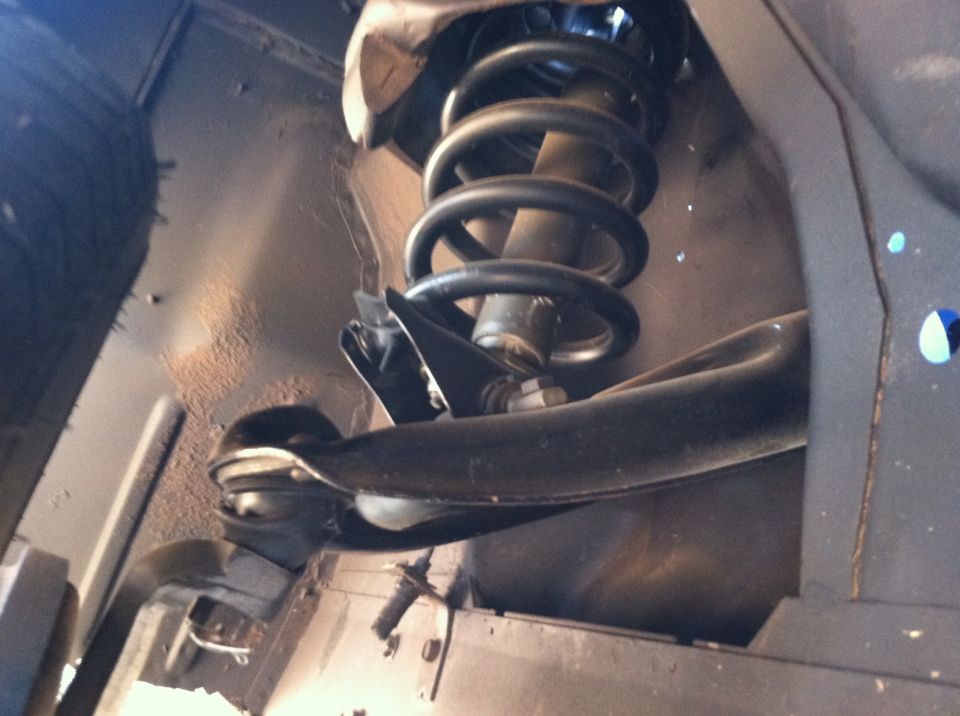 Close-up of a car's front suspension with a coil spring and shock absorber