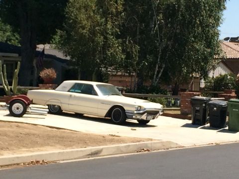 1968 Ford Mustang - A white 1963 Ford Thunderbird convertible is parked with a small trailer attached.
