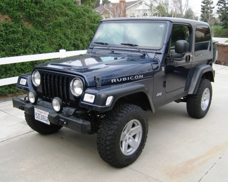 Dark blue 2003 Jeep Wrangler Rubicon with a black hardtop, front 3/4 view, parked on a concrete driveway