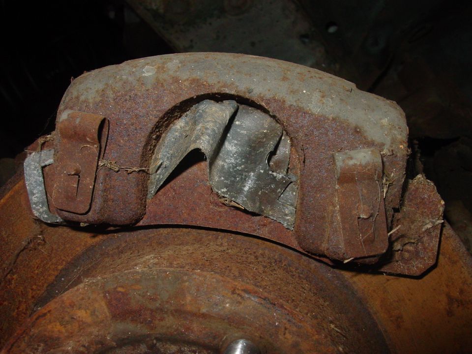 Heavily rusted brake caliper assembly over a brake rotor