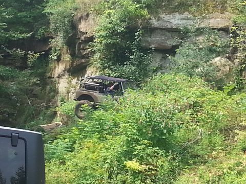 1996 Ford Bronco - An off-road vehicle navigates a challenging, vegetated cliffside.