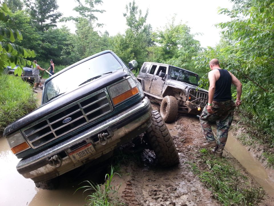 Ford F-series truck stuck in mud next to a Jeep. License plate 308XCC